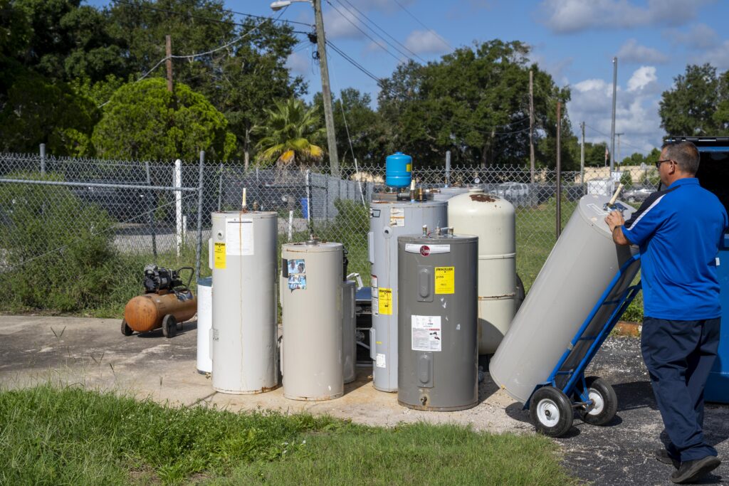 Several residential water heaters lined up outdoors for plumbing service or installation work.