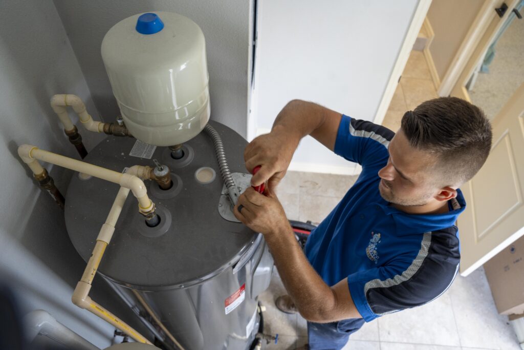 A Clean Plumbers technician repairing plumbing beneath a residential sink.